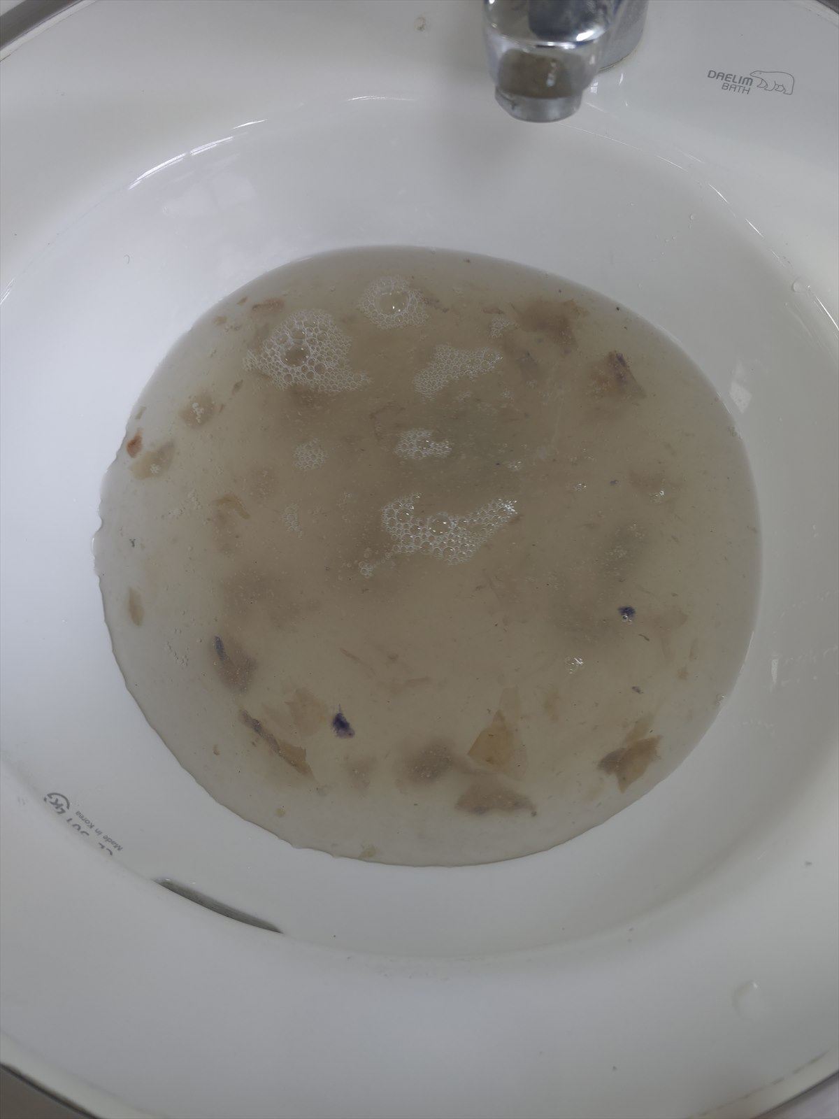 세관 후 받아낸 물에 갈색 이물질이 떠 있는 모습